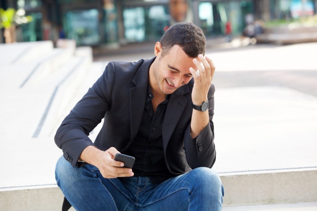 happy man laughing with cellphone outside