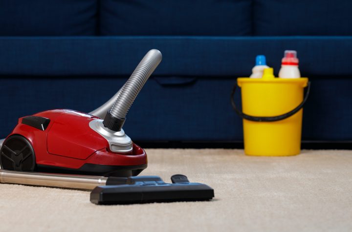 Red vacuum cleaner on a beige carpet