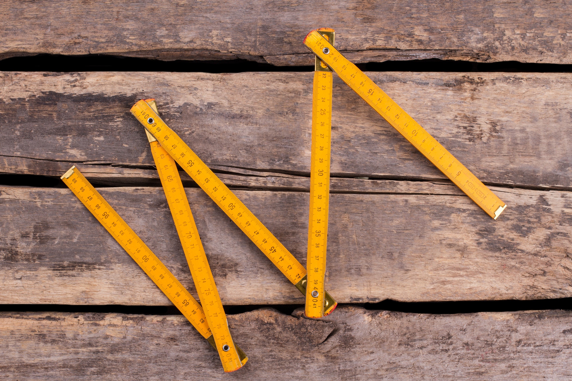 Yellow folding ruler on wooden boards background