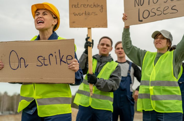 Group of employees in workwear carrying placards during strike