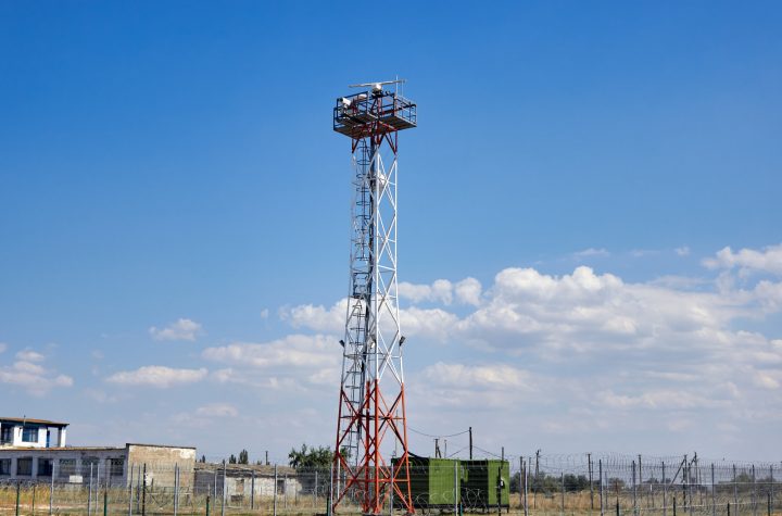 A working base station for Internet and mobile communications. High tower in the field.