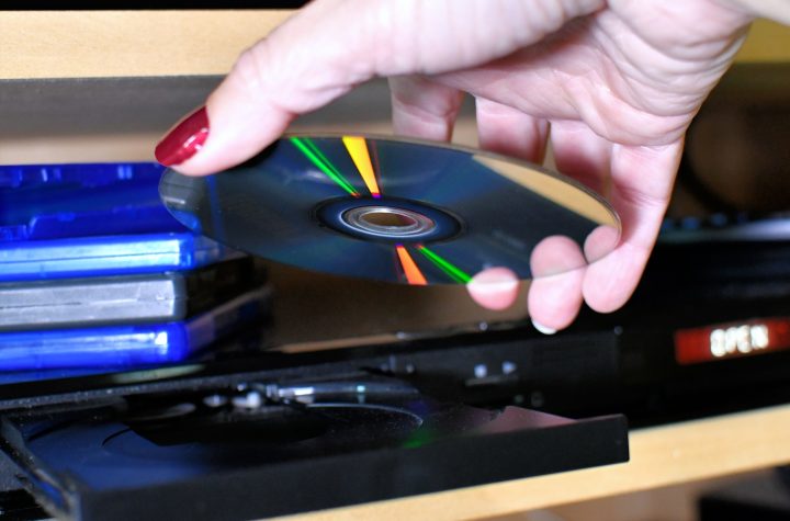Woman putting a Blu-ray DVD disc into a player for movie night.