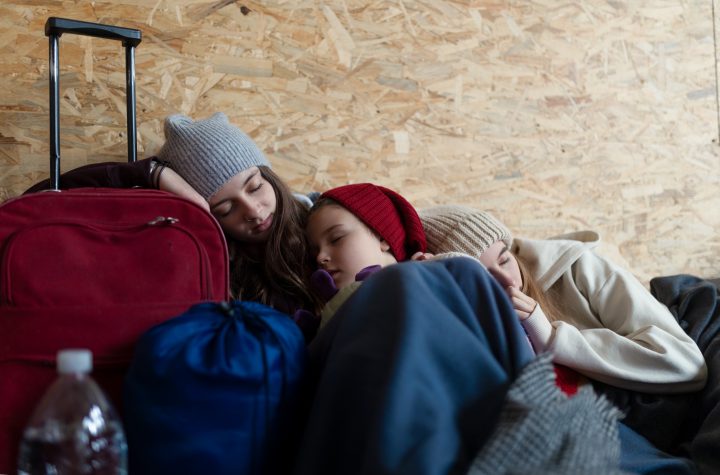 Ukrainian war refugees in temporary shelter and help center, children tired and sleeping