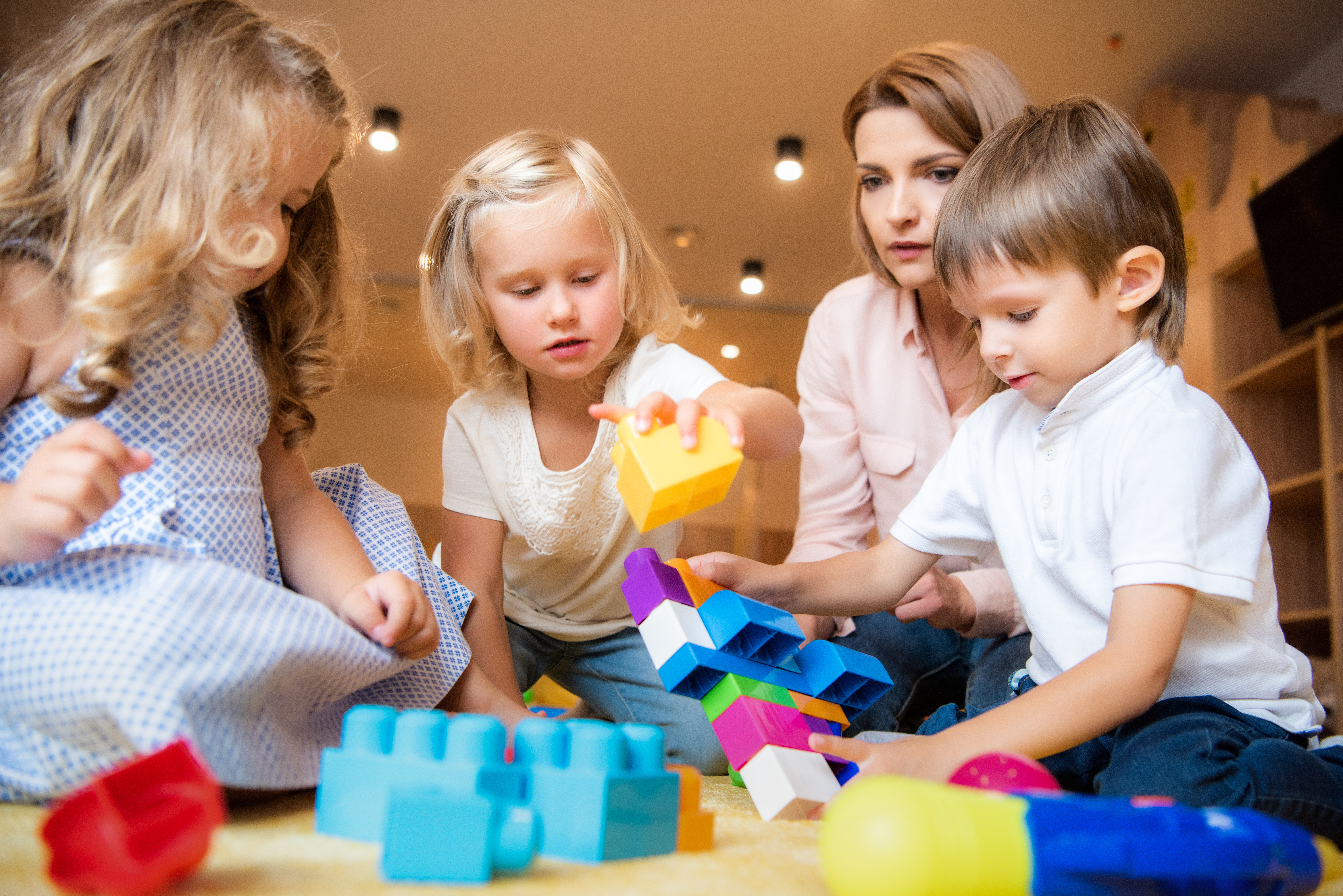 surface level of tutor and children playing with constructor in kindergarten