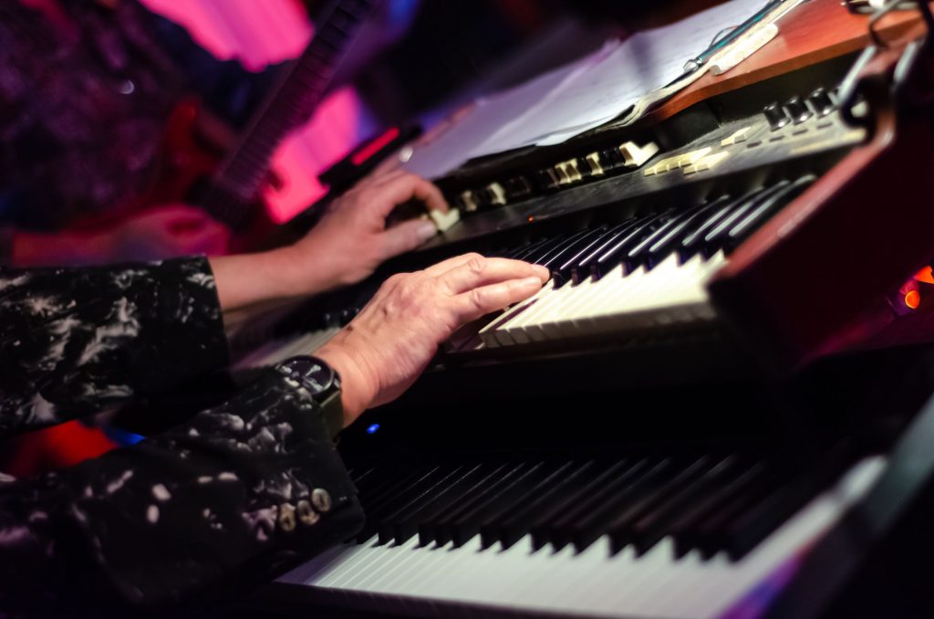 Mature woman playing the hammond organ with a guitarist in the background