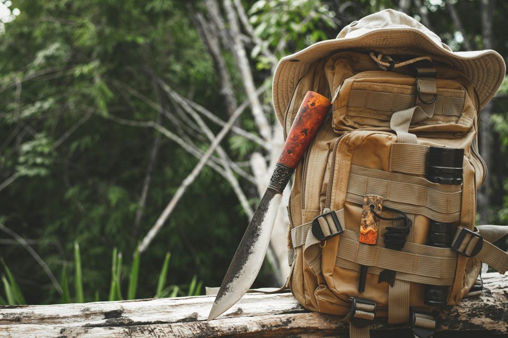 A knife backpack with equipment for survival in the forest on an old timber wooden