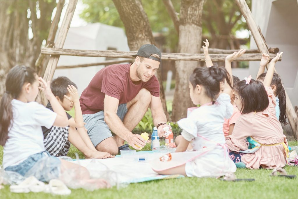 Pleasant man conducting a lesson for thai children outdoors
