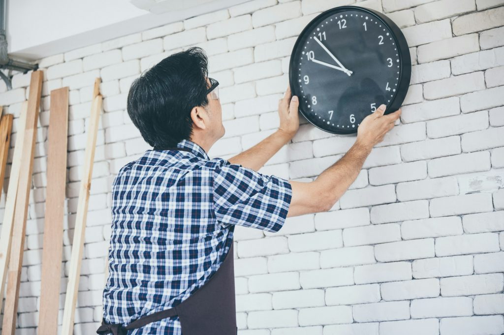 Grandfather repair and hanging clock on the wall at home, sets time clock