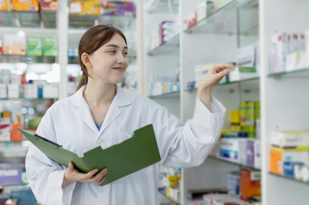 woman pharmacists working are select medications on shelf in drug store.