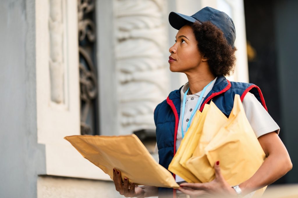 African American postal worker delivering mail in the city.