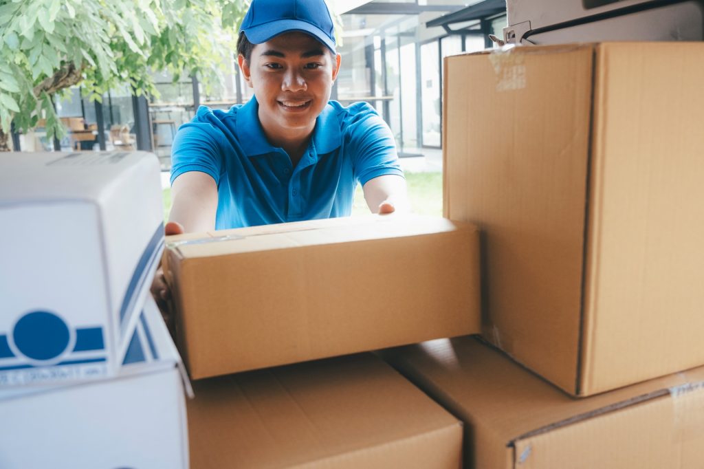 Delivery man loading cardboard boxes in a delivery van