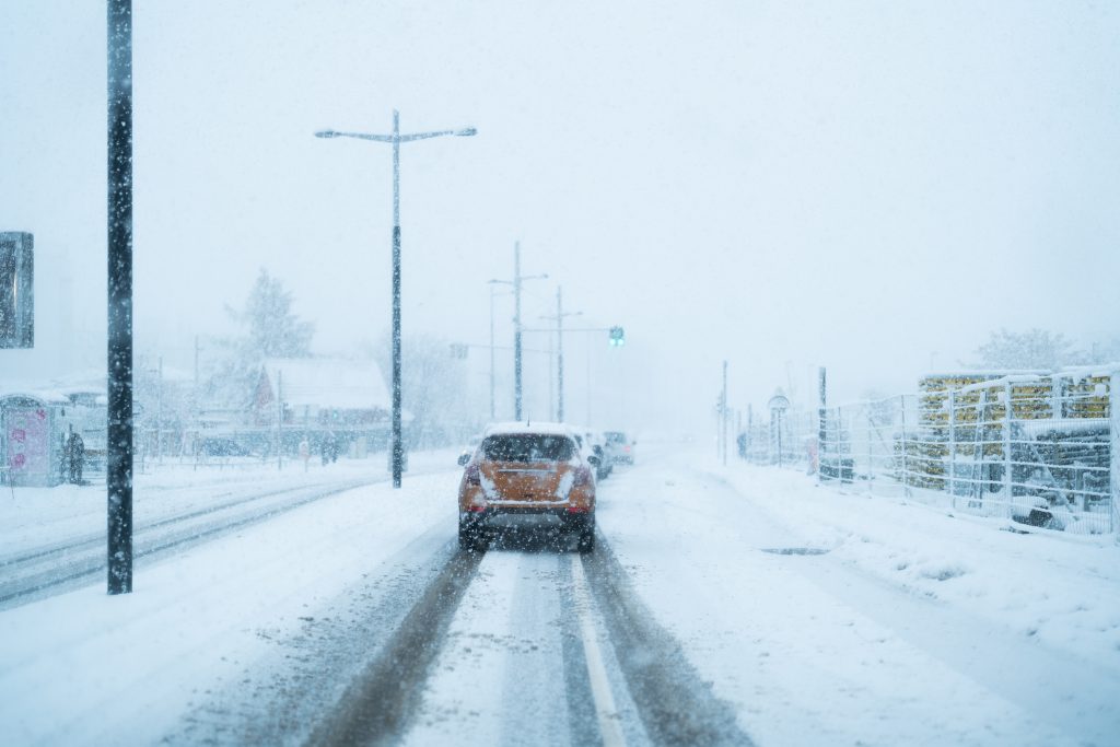 snow on street with a car