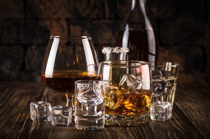 Set of strong alcohol drinks in glasses - whiskey, cognac, vodka, rum, tequila. Dark background.