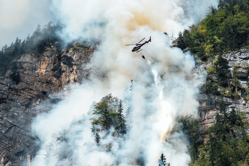 helicopter extinguishes forest fire on the slope of a fuming mountain, Löschhubschrauber