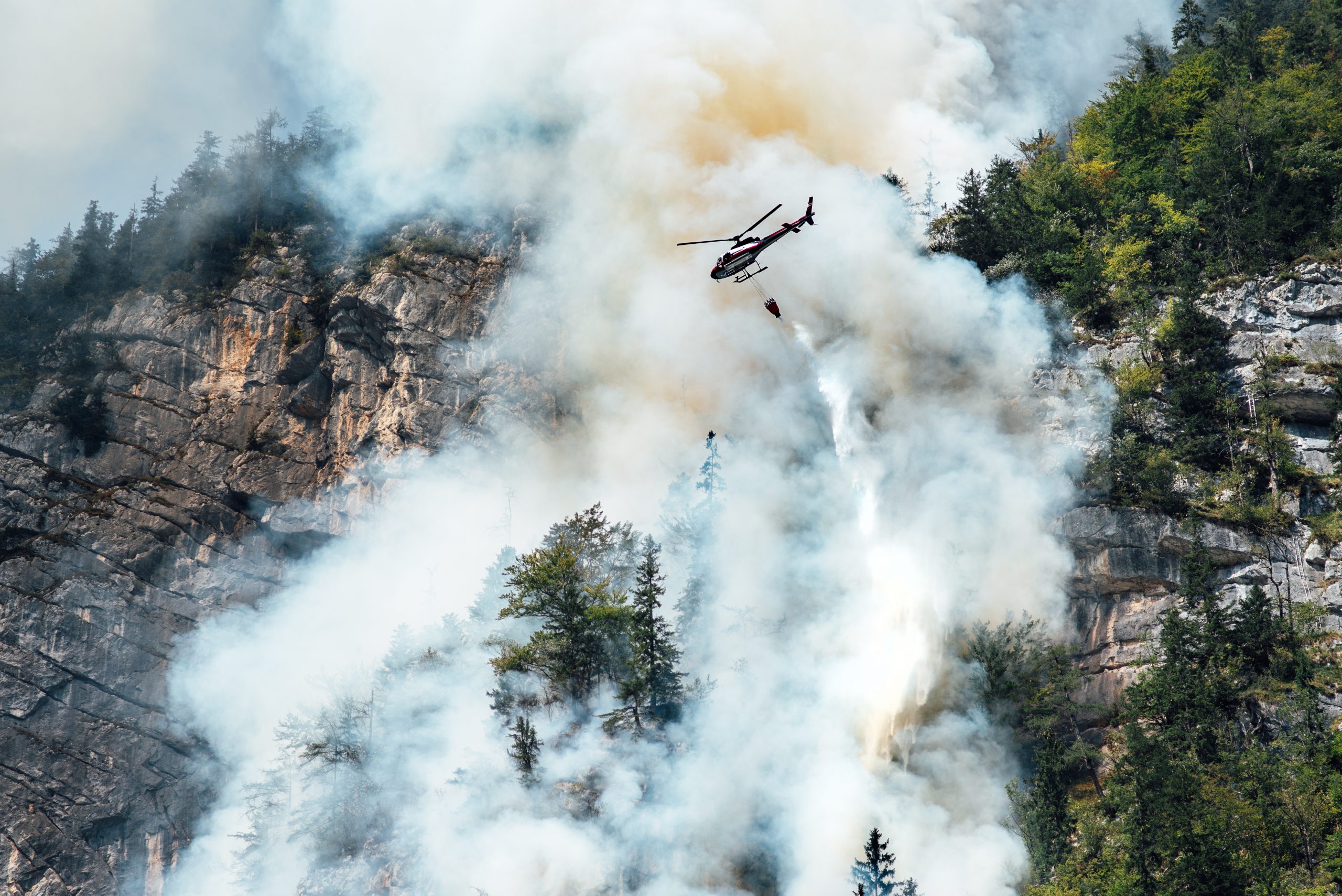 helicopter extinguishes forest fire on the slope of a fuming mountain, Löschhubschrauber
